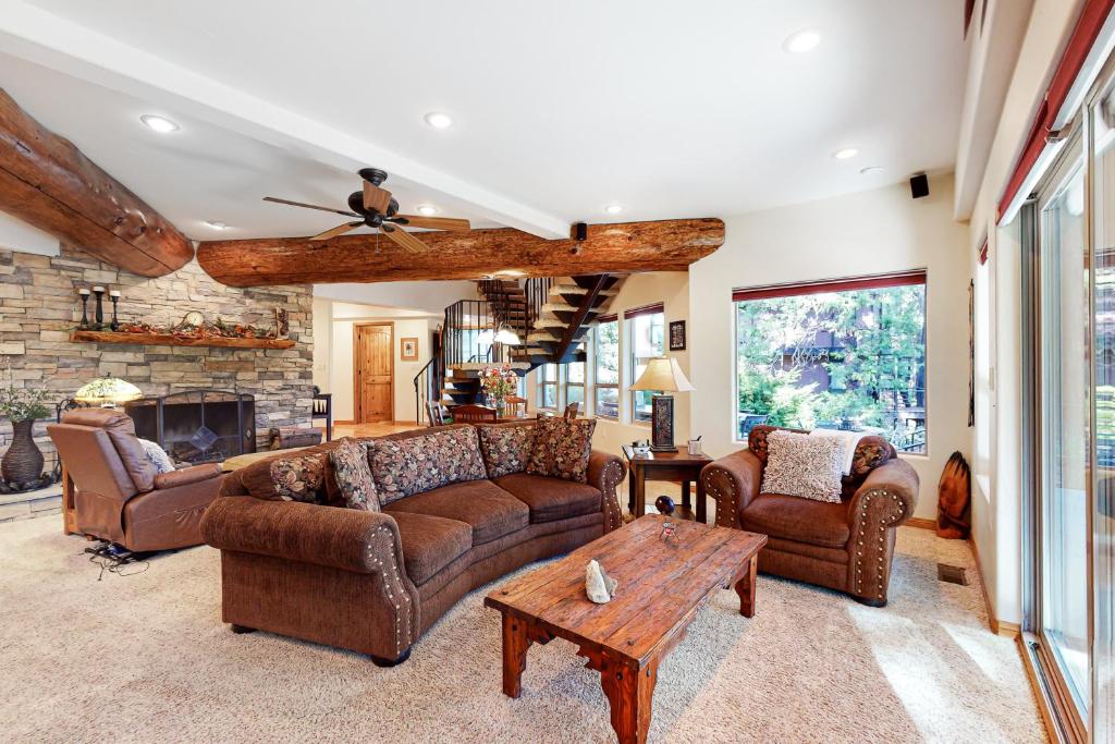 sala de estar con muebles de cuero y chimenea de piedra. en Arrowhead Dream, en Lake Arrowhead