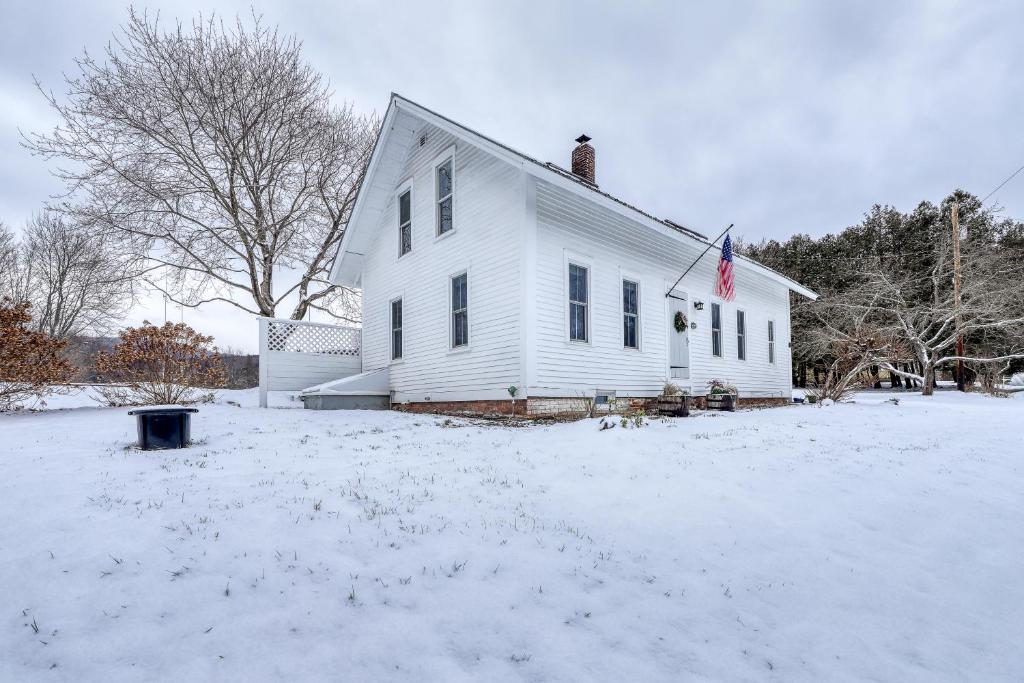 une maison blanche avec drapeau dans la neige dans l'établissement The Adams Mill Farm House, à Stowe