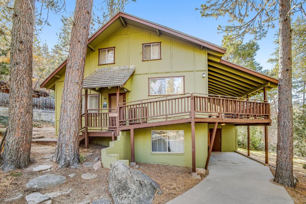 a yellow house with a deck in the woods at Meadow Creek House in Idyllwild