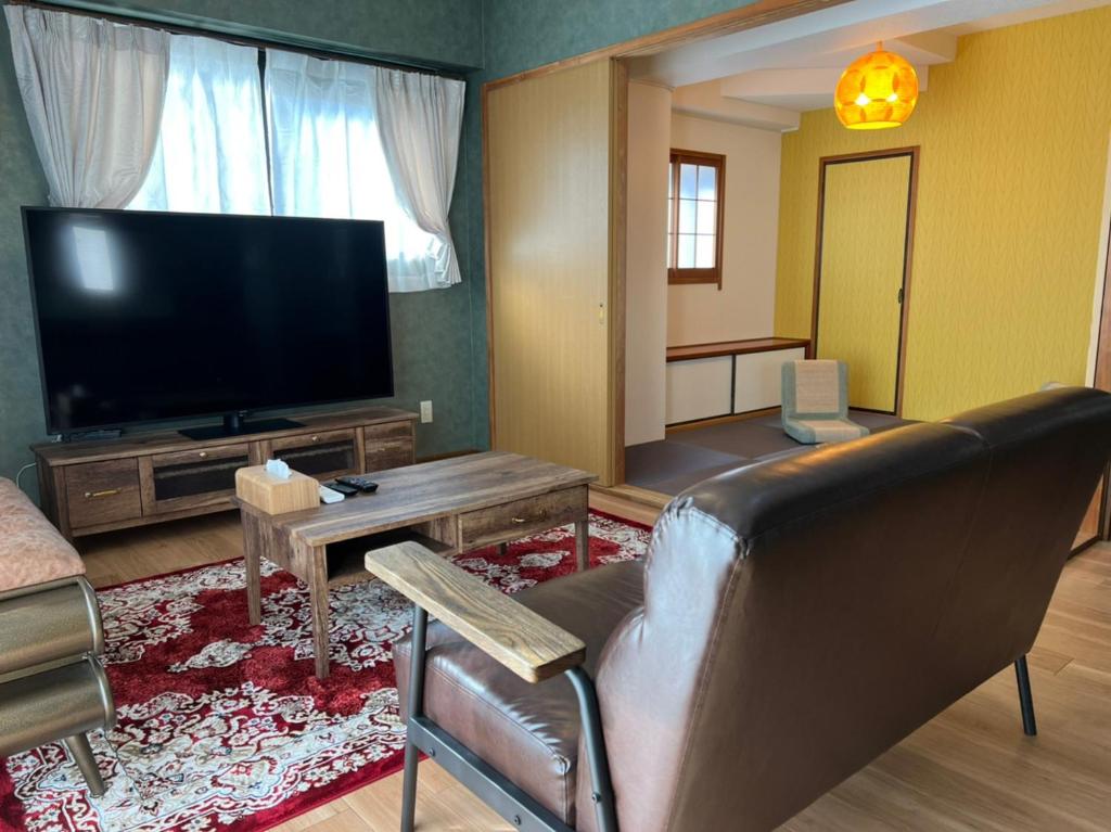 uma sala de estar com um sofá e uma televisão de ecrã plano em Parkside Inn Hakata No5 em Fukuoka