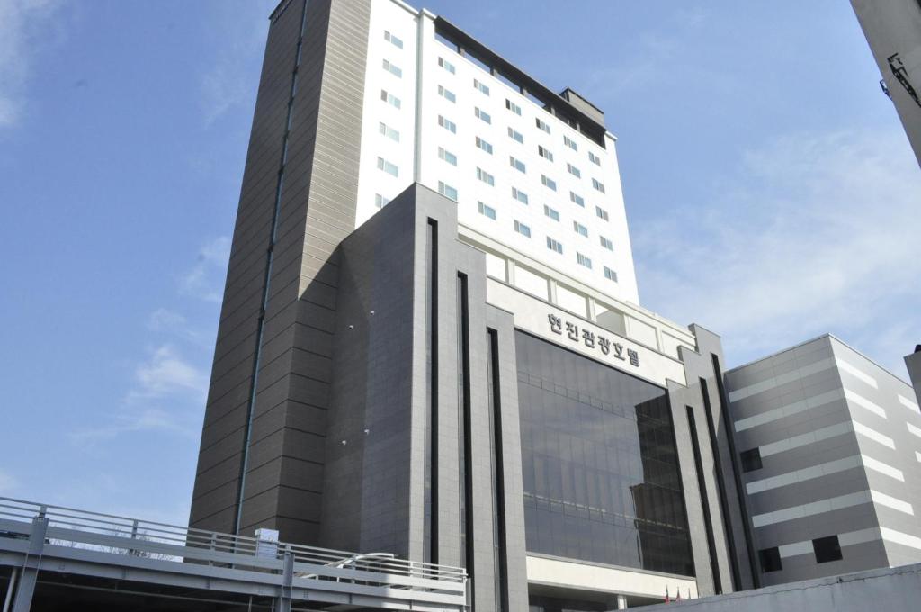 un edificio blanco alto con un puente delante de él en Hyunjin Tourist Hotel, en Donghae