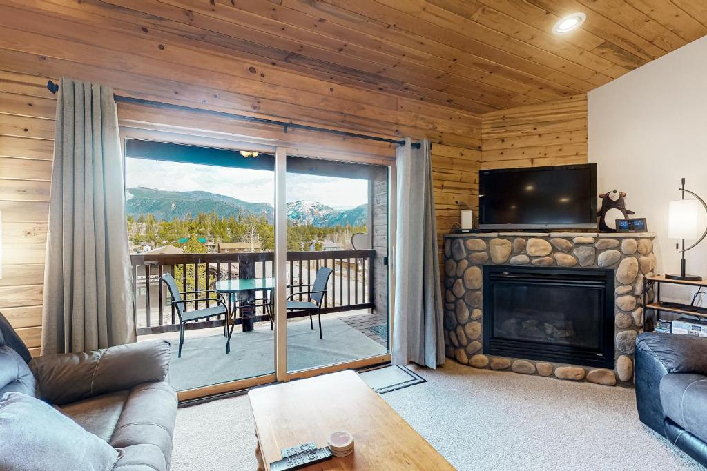 a living room with a fireplace and a view of a deck at Bald Mountain Views in Grand Lake