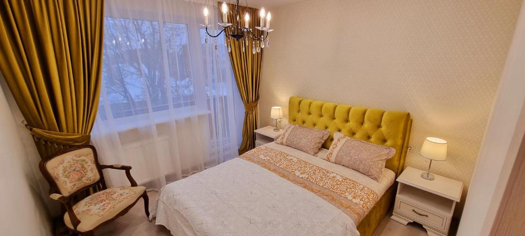 a bedroom with a bed with a yellow headboard and a window at A. G. Central Apartaments in Šiauliai