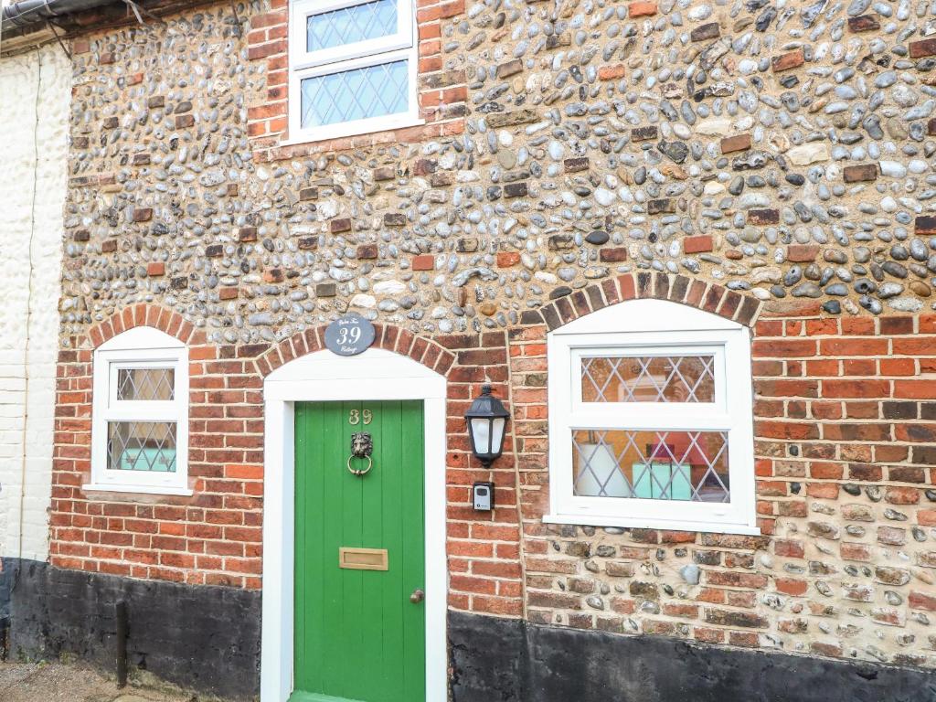 a brick building with a green door and two windows at Palm Tree Cottage in Great Yarmouth