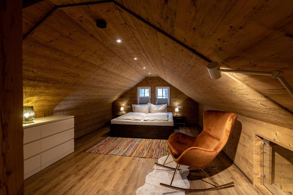 een zolderkamer met een bed en een stoel bij Cottage am Heiderand in Dresden