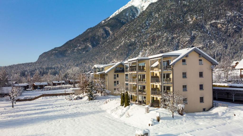un bâtiment dans la neige devant une montagne dans l'établissement Apartments Schluga, à Hermagor