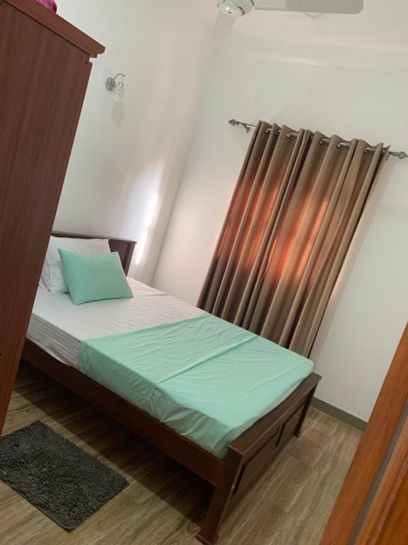 a small bedroom with a bed and a curtain at Zentinal in Unawatuna