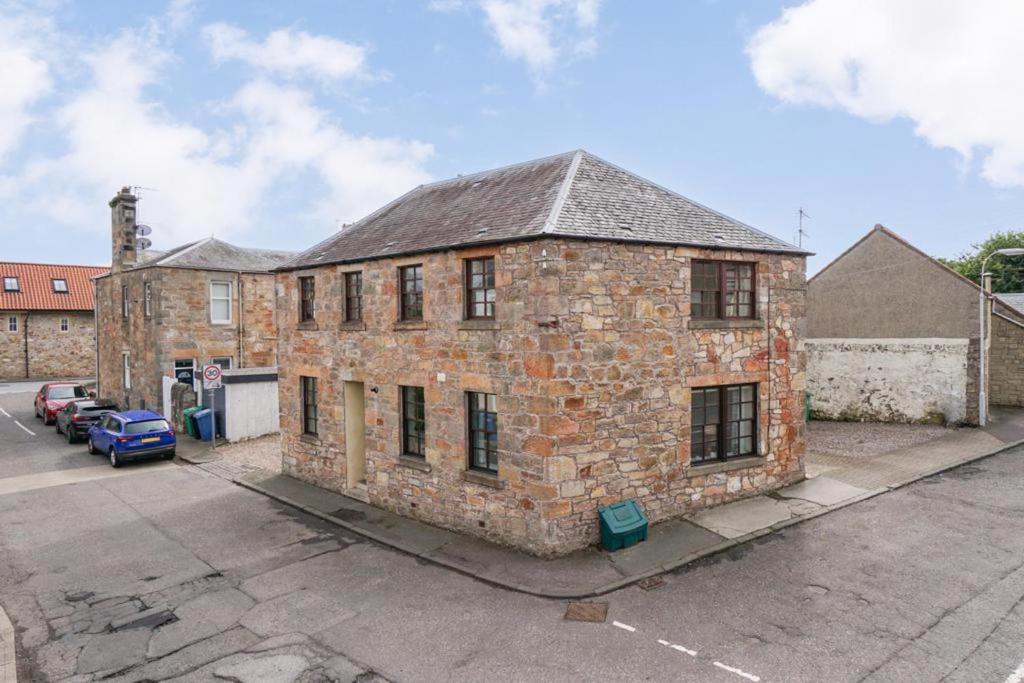 an old brick building sitting in a parking lot at The Howff - Lovely 2-Bed Apartment in Anstruther in Anstruther