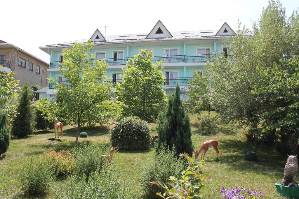 a building with two horses grazing in a garden at Green Hotel in Almaty
