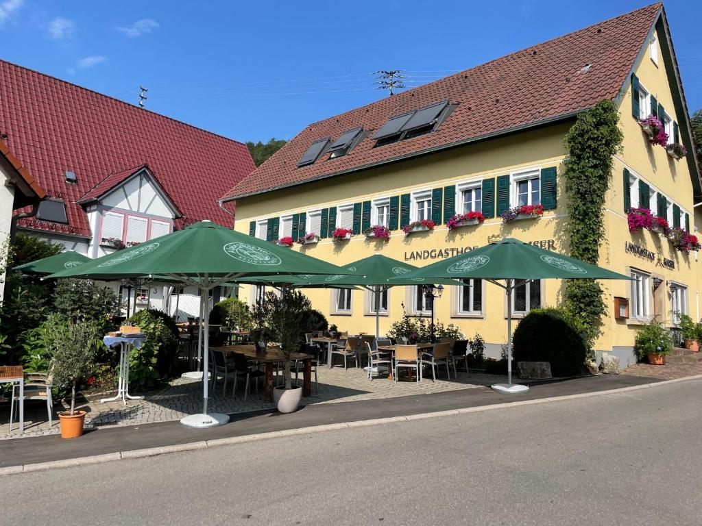 un edificio amarillo con sombrillas verdes delante en Landgasthof Kaiser, en Bieringen