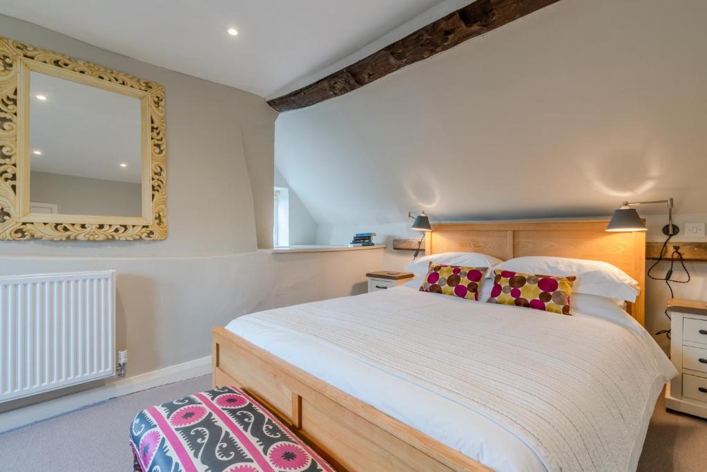a bedroom with a large bed and a mirror at Corner Cottage in Bretforton