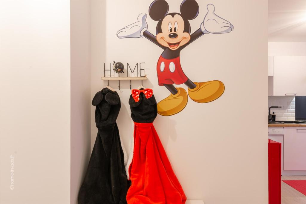 a wall with a mickey mouse sign and two dresses at Bienvenue chez Mickey ! in Montévrain