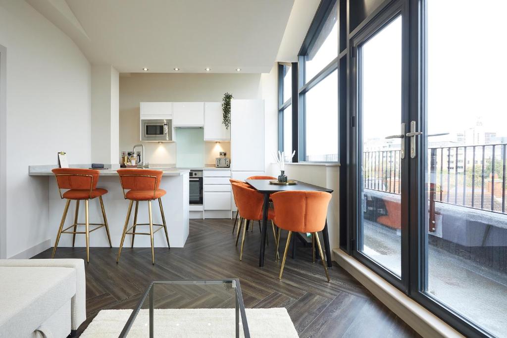 a kitchen and living room with orange chairs and a table at Humber Lofts Apartments in Hull