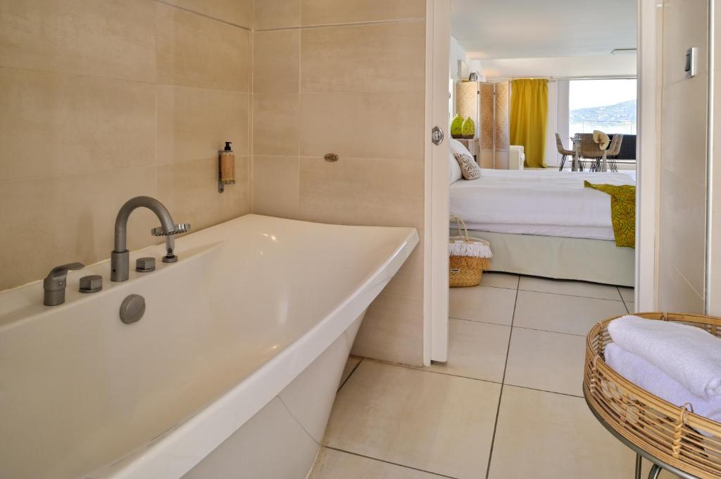 a bathroom with a bath tub and a bedroom at L&#39;Escale Côté Sud in LʼÎle-Rousse