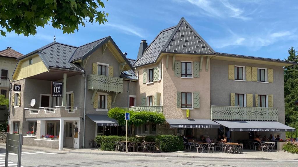 a building with tables and chairs in front of it at Logis La Chaumière Saint-Maurice in Thorens-Glières