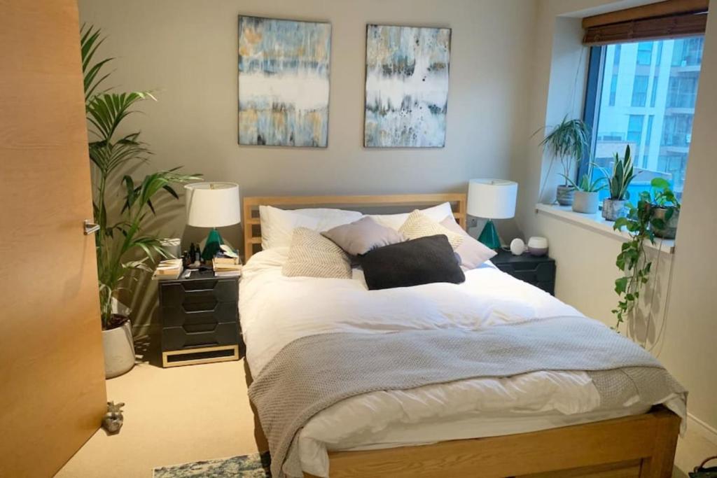 a bedroom with a bed with two lamps and plants at Modern 3 Bedroom Apartment in Paddington in London