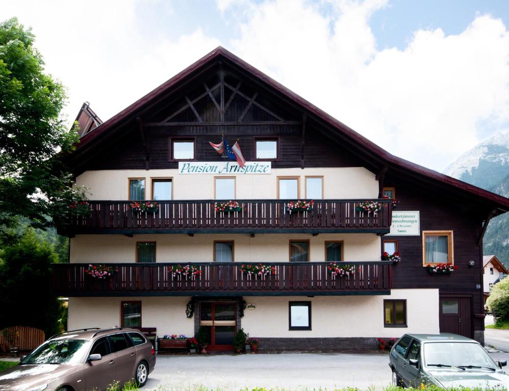 een gebouw met een balkon en auto's geparkeerd voor het gebouw bij Pension Arnspitze in Scharnitz