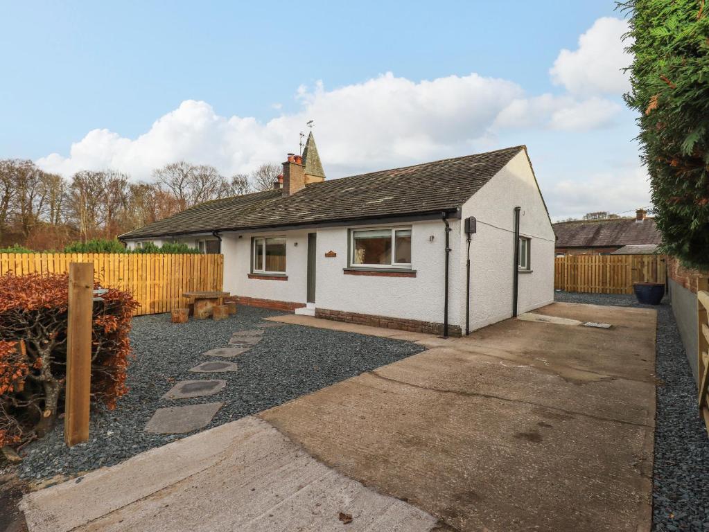 una casa blanca con una valla en un patio en Woodview en Pooley Bridge