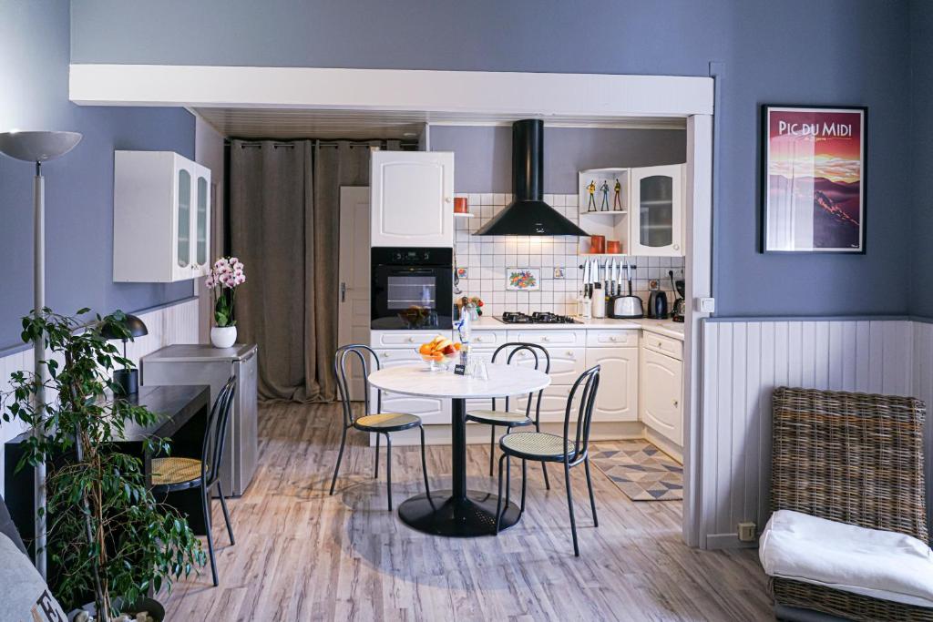 eine Küche mit einem Tisch und Stühlen im Zimmer in der Unterkunft Le Pyrénées - Bel appartement à proximité des Halles - Parking in Pau