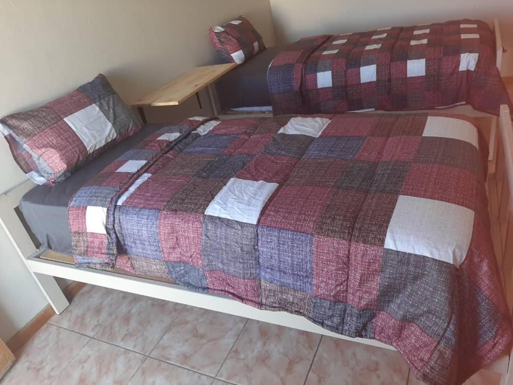 Bett mit einer karierten Bettdecke in einem Zimmer in der Unterkunft OrbanLife Lite Keetmanshoop in Keetmanshoop