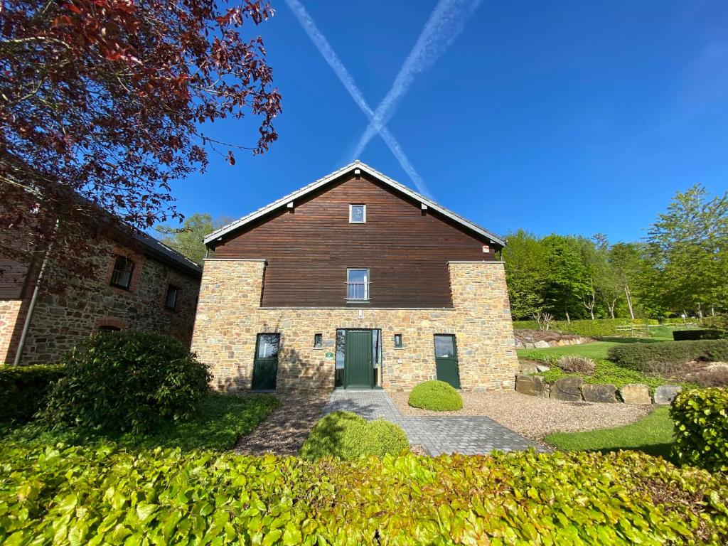 a large brick house with green doors in a yard at Gite Du Moulin Coquelicot in Stavelot