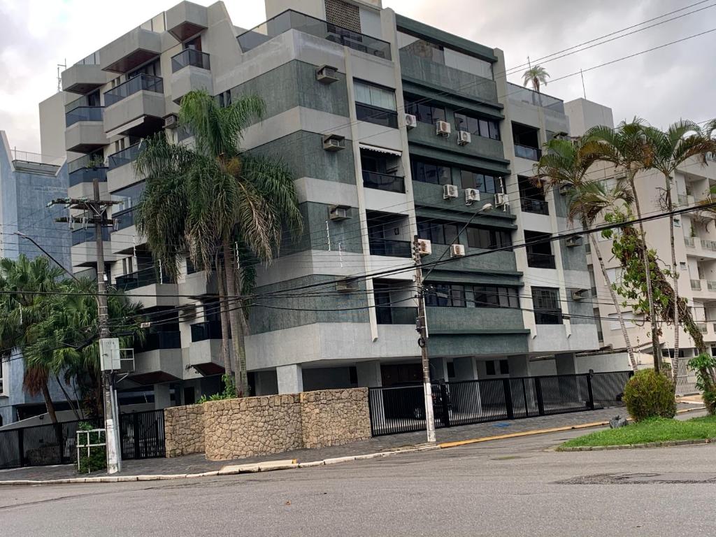 um edifício de apartamentos com palmeiras em frente em Apartamento na Praia da Enseada - Guarujá SP no Guarujá