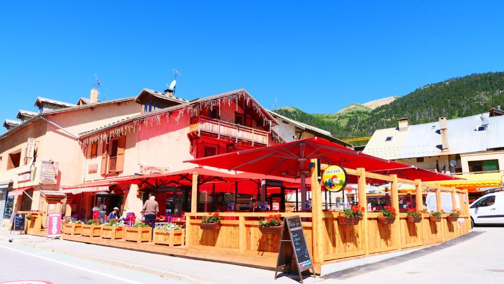 um restaurante com guarda-sóis vermelhos em frente a um edifício em Hôtel Alpis Cottia em Montgenèvre