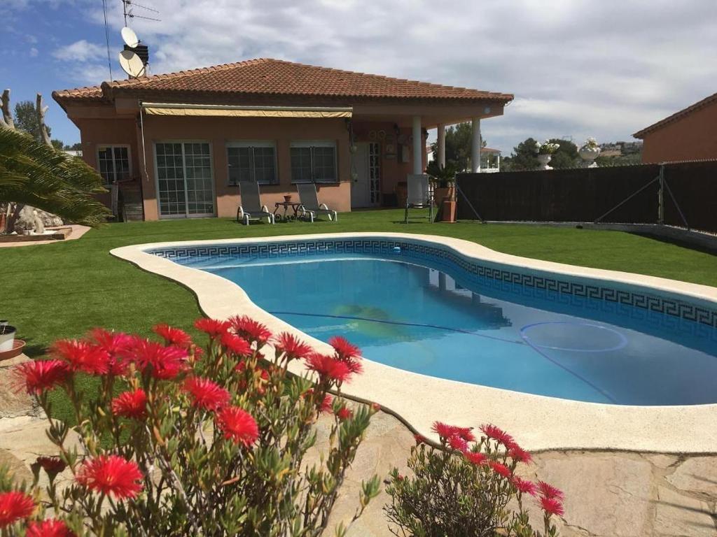 uma piscina em frente a uma casa com flores vermelhas em Vama House em Canyelles