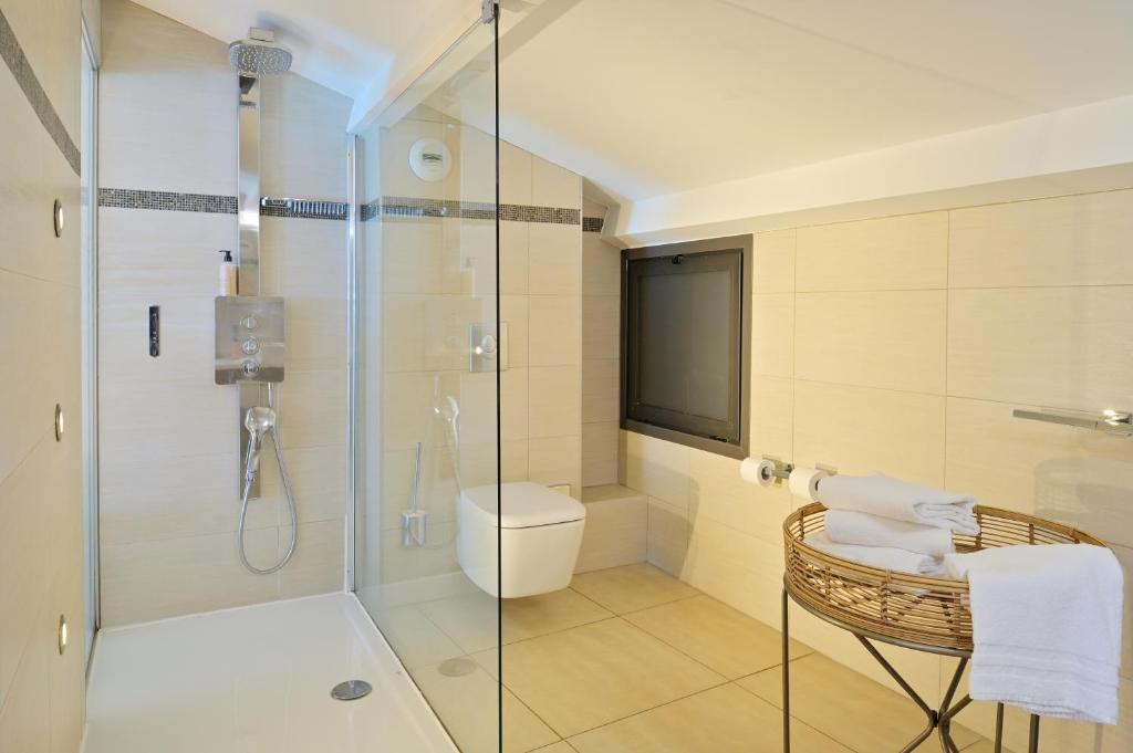 a bathroom with a glass shower with a toilet and a chair at L&#39;Escale Côté Sud in LʼÎle-Rousse