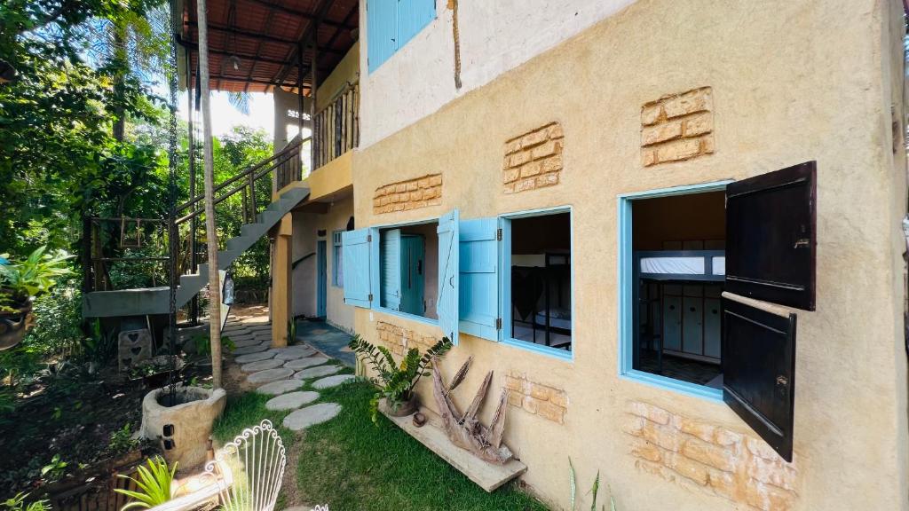 un bâtiment avec des fenêtres bleues et une cour dans l'établissement Eco Casa di Barro Hospedagem e Hostel, à Île de Boipeba