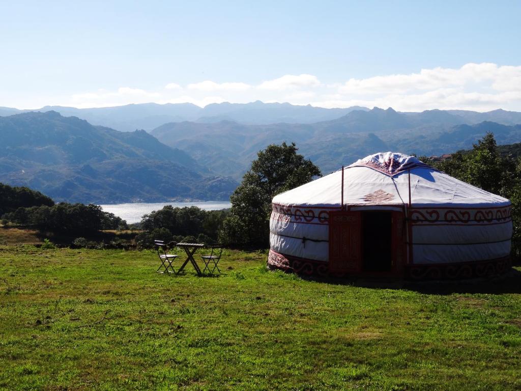 a yurt in a field with a table and a view at Nomad Planet in Fiães do Rio