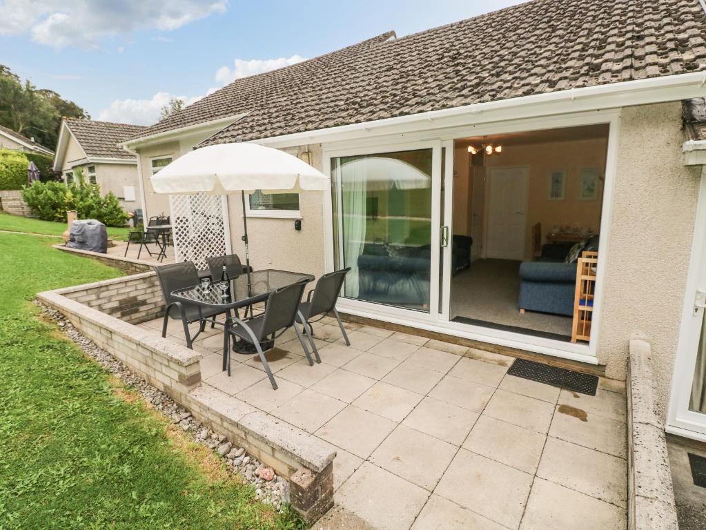 un patio con tavolo, sedie e ombrellone di Number 6 Oxwich Leisure Park a Swansea