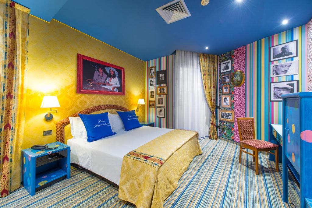 a hotel room with a bed with blue pillows at Admiral Art Hotel in Rimini