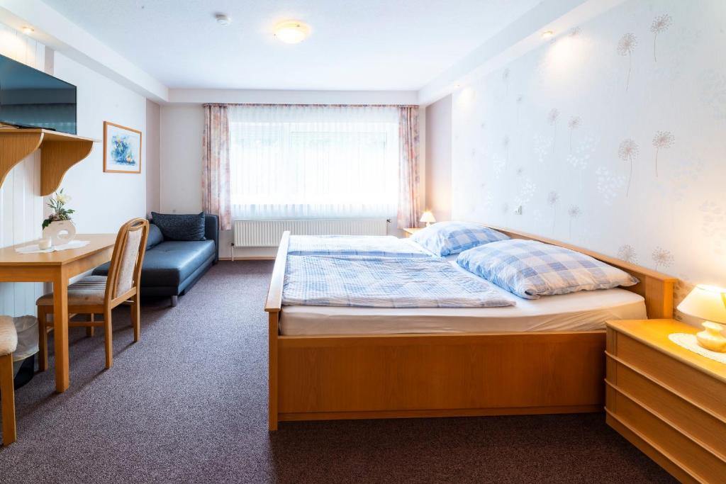 a bedroom with a bed and a table and a desk at Gästezimmer 3 im Landgasthaus Lindenhof in Fresenburg