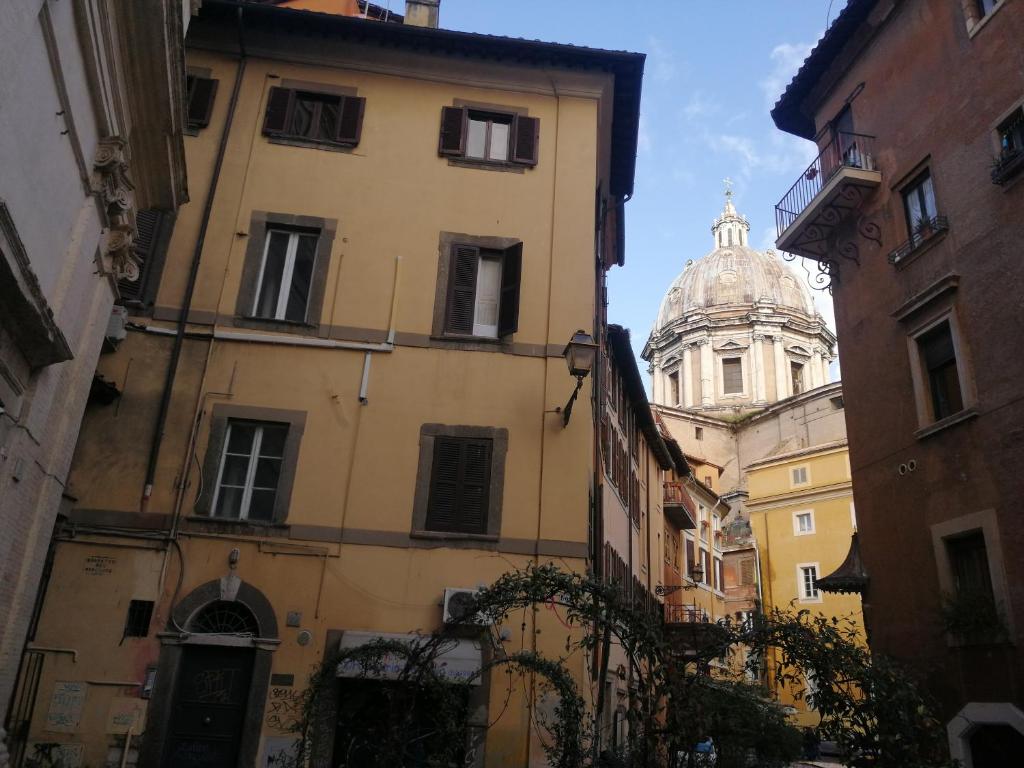 une allée entre deux bâtiments avec une cathédrale en arrière-plan dans l'établissement RomAmoR Campo de' fiori, à Rome