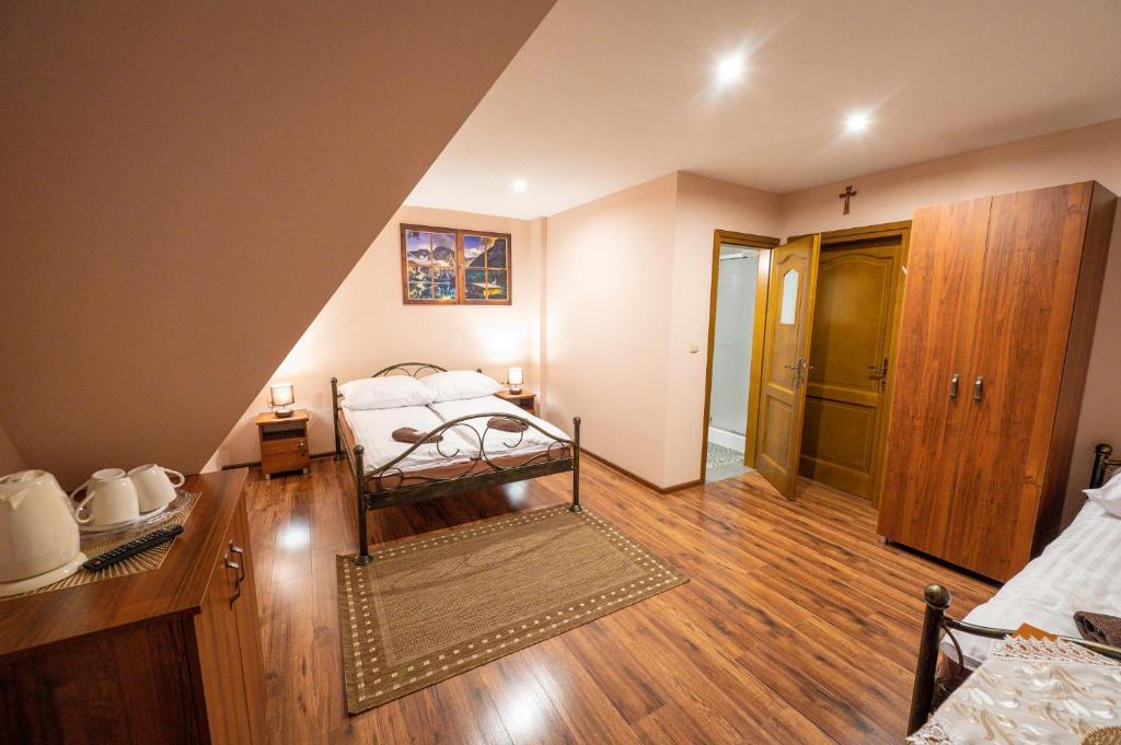 a bedroom with a bed and a wooden floor at Pokoje Gościnne Skalne Podhale in Bukowina Tatrzańska