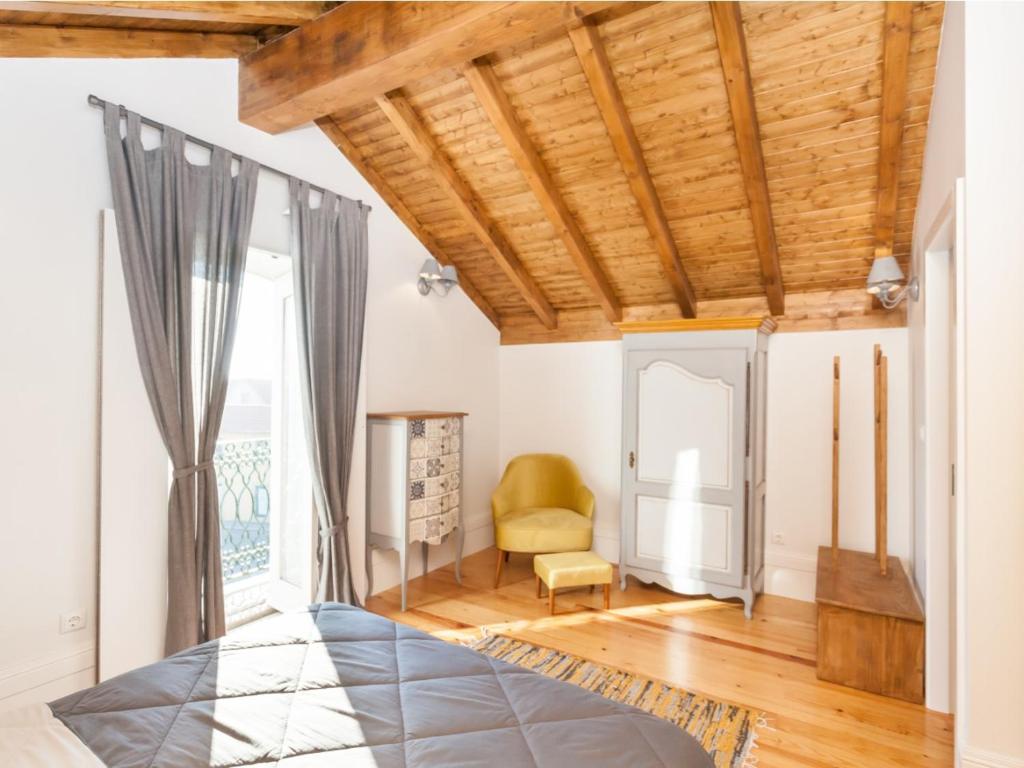 a living room with a wooden ceiling and a chair at Castle Beach House in Leça da Palmeira