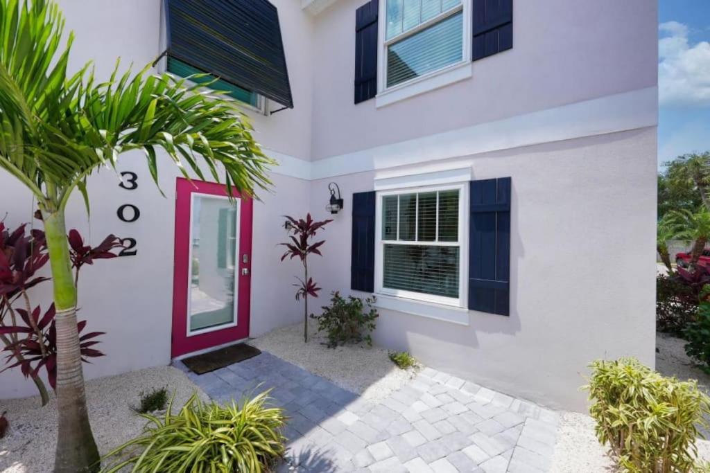 a white house with a red door and a palm tree at Canal Lower-Gorgeous 3 bed 3 bath near SK Village in Siesta Key