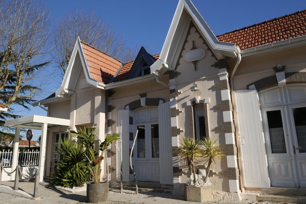 een wit huis met een rood dak bij Hôtel Villa Teranga in Andernos-les-Bains