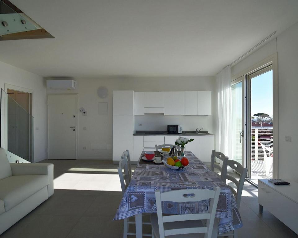 Il comprend une cuisine et un salon avec une table et des chaises. dans l'établissement Residence Al Molo - Suite Porta del Mar Sea View - Agenzia Cocal, à Caorle