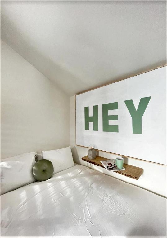 una cama blanca con un cartel en la pared en Hey Studio - Free Parking and free Netflix en Aveiro