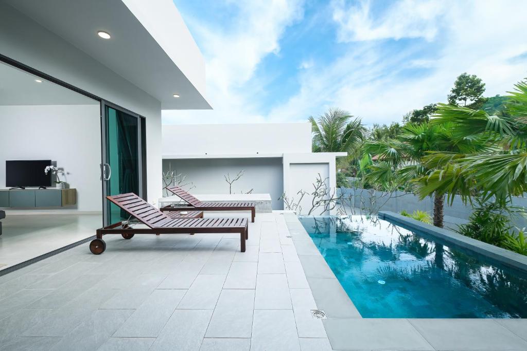 ein Haus mit einem Pool und zwei Stühlen in der Unterkunft T villas in Thong Nai Pan Yai