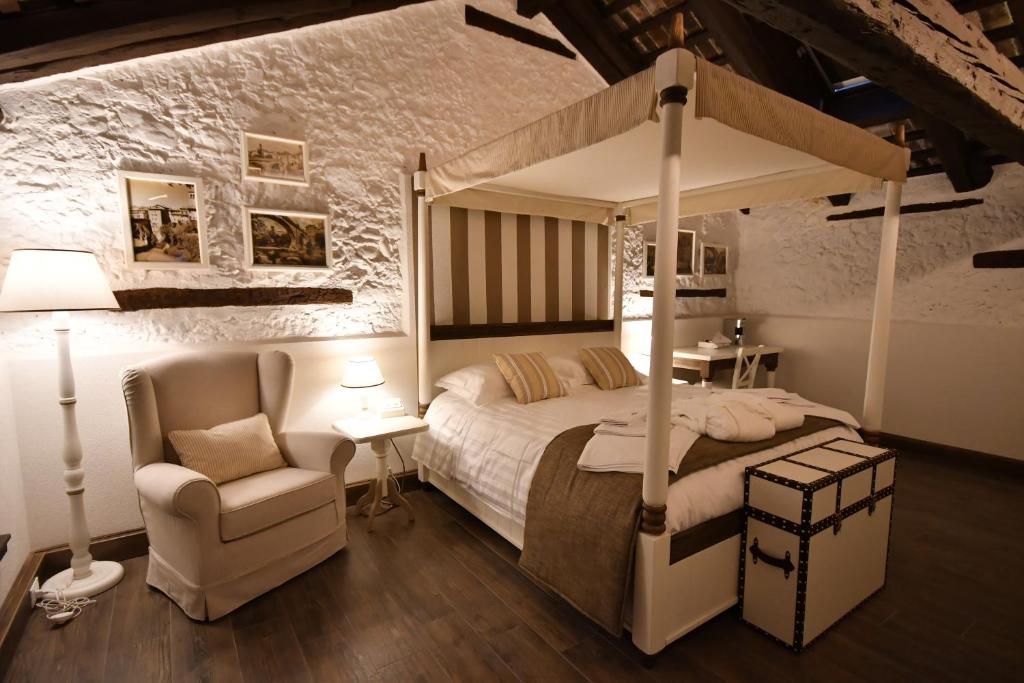 een slaapkamer met een hemelbed en een stoel bij Al Palazzetto in Udine