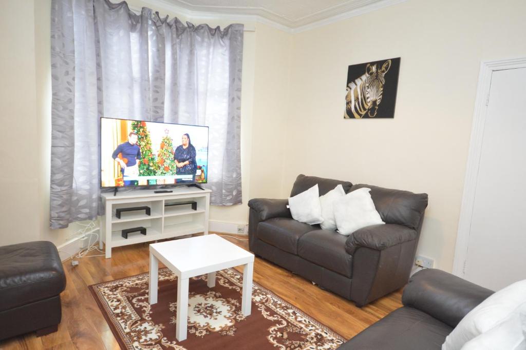 ein Wohnzimmer mit einem Sofa und einem TV in der Unterkunft Cheerful 4 bedroom House in greater London in London