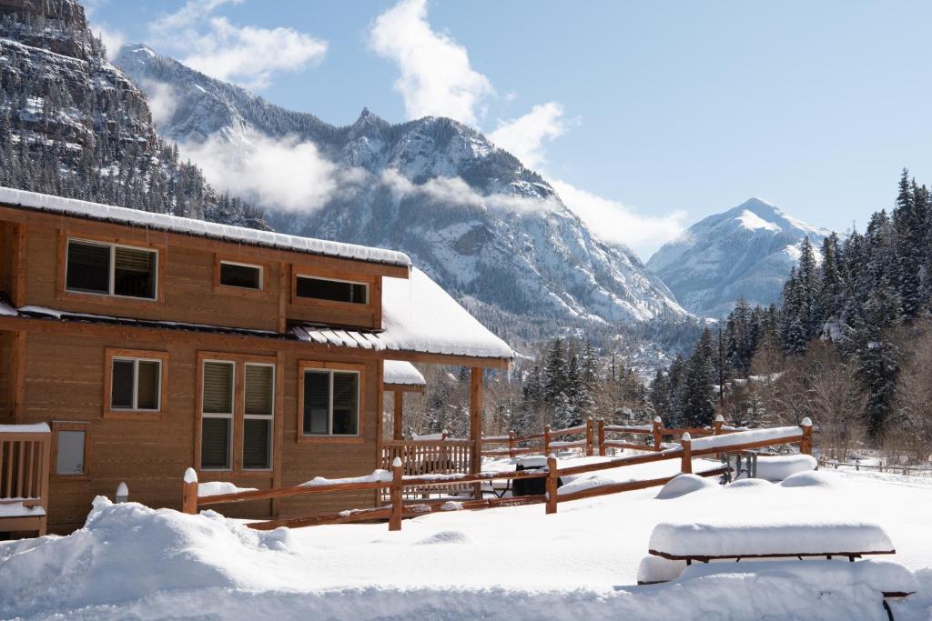 a cabin in the snow with mountains in the background at Ouray Riverside Resort - Inn & Cabins in Ouray