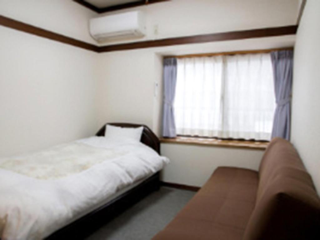 um pequeno quarto com uma cama e uma janela em Ryokan Seifuso - Vacation STAY 02201v em Matsumoto