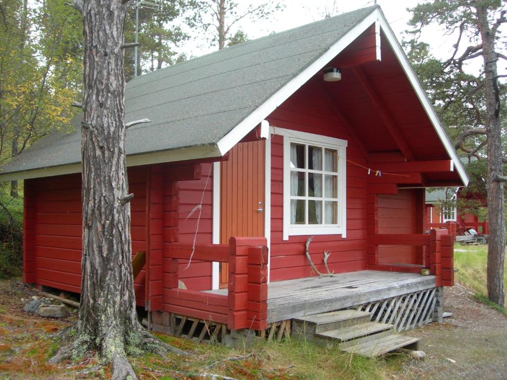 eine rote Hütte mit einer Veranda und einem Fenster in der Unterkunft Kenestupa Matkailukeskus in Utsjoki