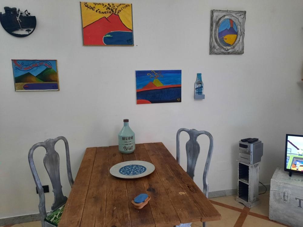 een houten tafel en stoelen in een kamer met schilderijen bij La casa nella roccia in Napels