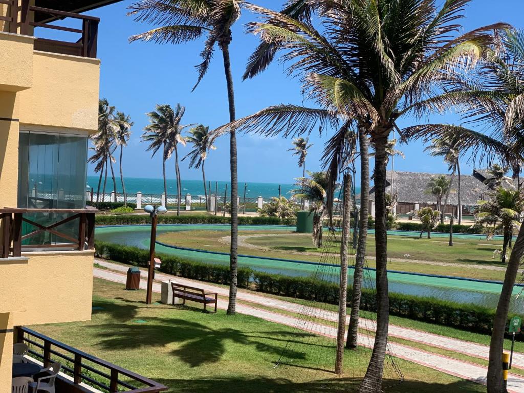 阿基拉斯的住宿－Apartamento no Aquaville Resort, do lado da sombra e perto da praia，棕榈树建筑的阳台享有海滩美景。