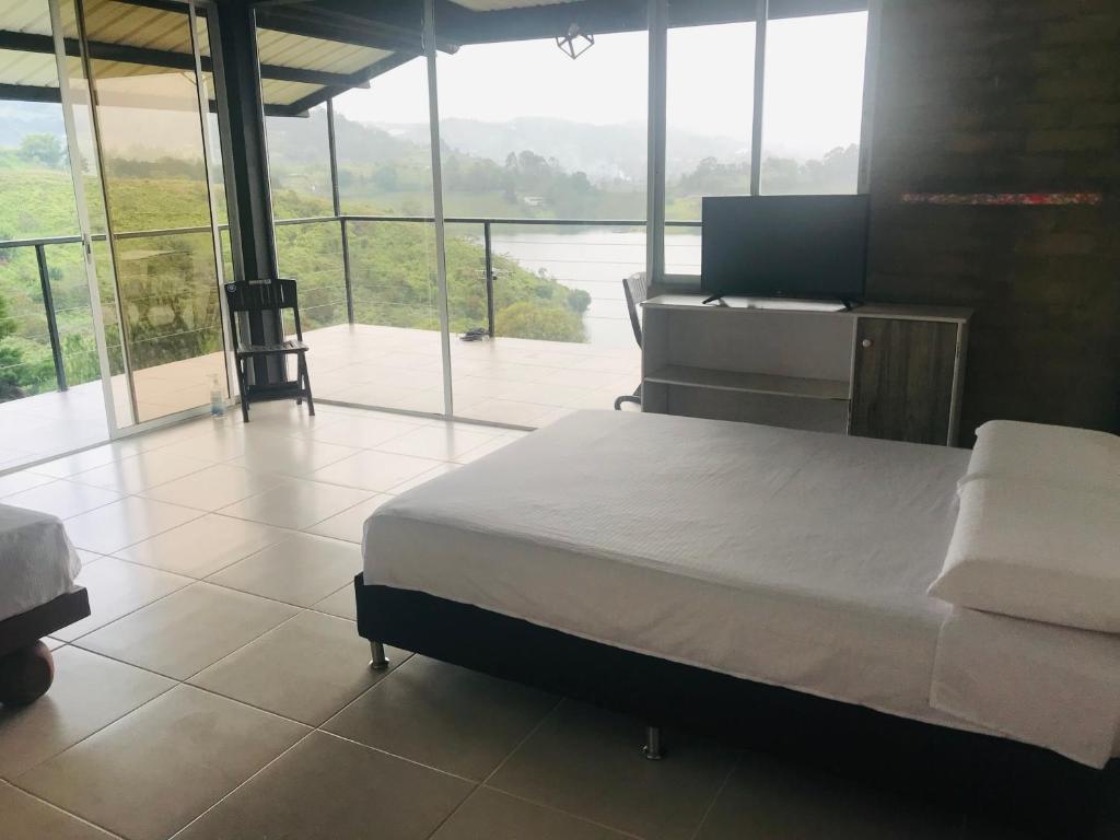 ein Schlafzimmer mit einem Bett, einem Schreibtisch und Fenstern in der Unterkunft El Espume de San Juan by JR in Guatapé